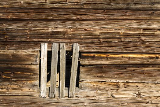 Old log wall background with a window nailed shut