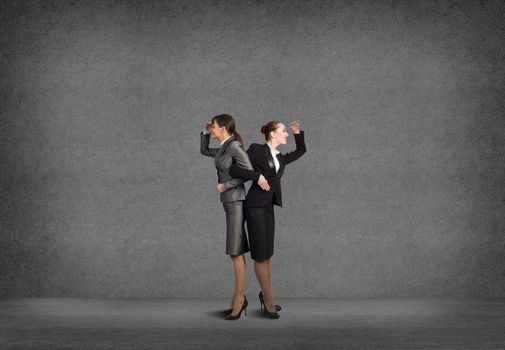 two business women holding hands, looking in different directions, teamwork