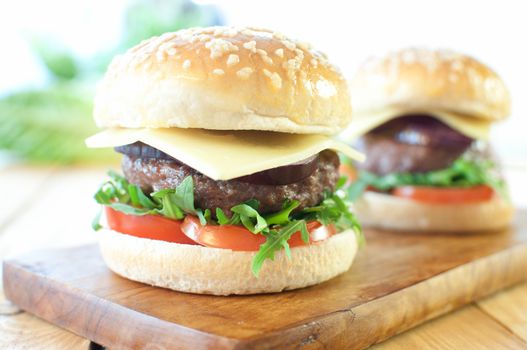 Freshly made hamburgers with tomatoes, red onion and cheese 
