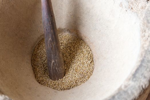 Big traditional stone mortar with fresh corn and wooden pestle