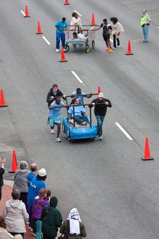 Lawrenceville, GA, USA - March 29, 2014:  High-angle view of two teams pushing beds down city street in the annual Lawrenceville Bed Race, to benefit a local Gwinnett County homeless shelter.