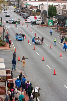 Lawrenceville, GA, USA - March 29, 2014:  High-angle view of two teams pushing beds down city street in the annual Lawrenceville Bed Race, to benefit a local Gwinnett County homeless shelter.