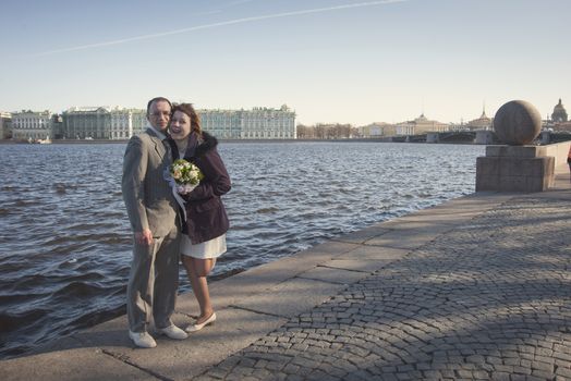 couple walk along the embankment of the river