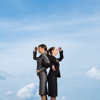 two business women holding hands, looking in different directions, teamwork