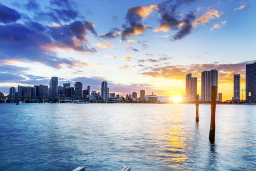 Miami city skyline panorama at dusk with urban skyscrapers over sea with reflection 