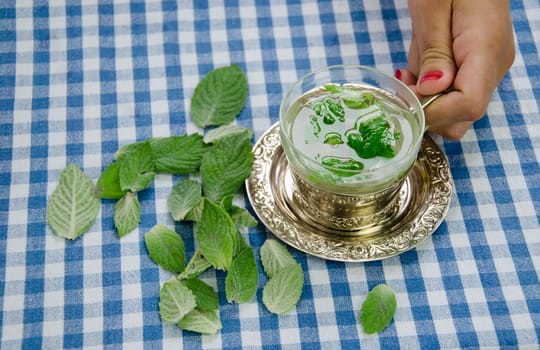 woman hand hold cup of handle with the healing relaxing aromatic mint tea