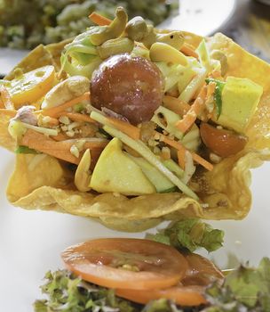 The angel fruity papaya salad is a kind of papaya salad for who want the nutrition and health serve in wonton bowl on plate.