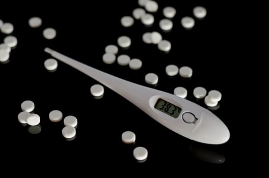 Thermometer and pills on a black background