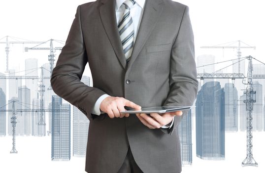 Businessman in suit hold tablet pc. Wire frame tower crane and skyscrapers on the background