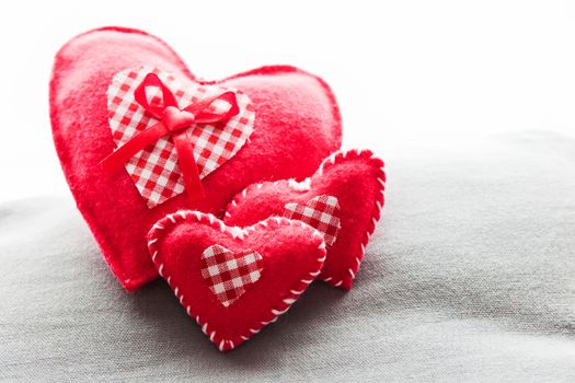 Handmade plush red hearts on the soft pillow. Romantic love, Valentine's Day concepts.