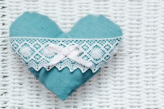 Vintage handmade plush turquoise heart on white rustic wicker. Romantic love, Valentine's Day concepts.