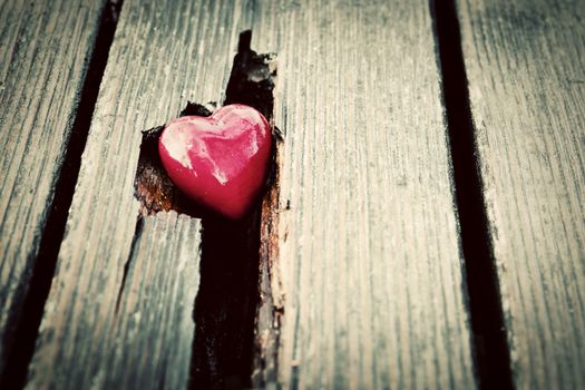 Red heart in crack of wooden plank. Symbol of love, Valentine's Day. Vintage style