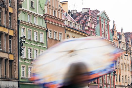 Wroclaw, Poland. A person with umbrella on the rainy market square with colorful historical buildings