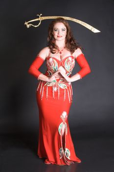 Belly Dancer in red costume balancing a tribal sword