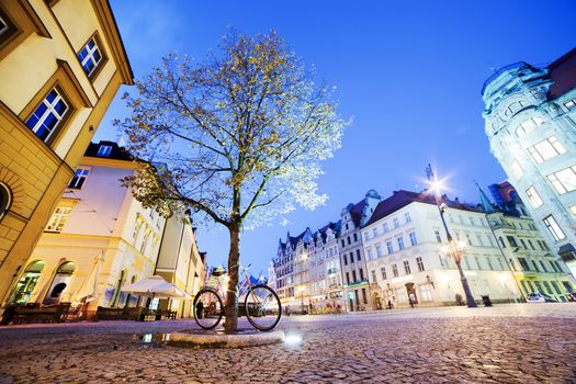 Wroclaw, Poland. The market square with historical buildings, tree and bike at night. Silesia region.