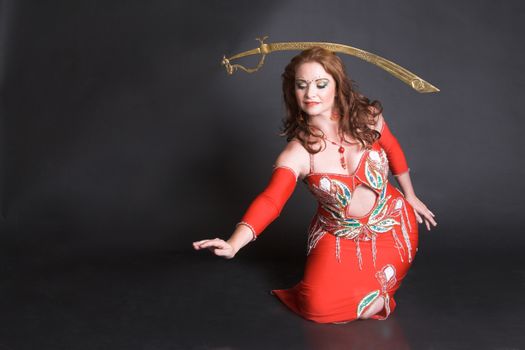 Belly Dancer in red costume balancing a tribal sword