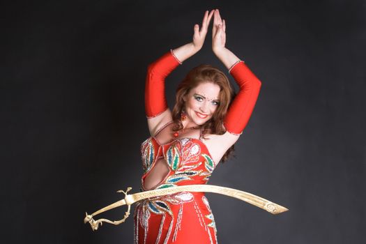 Belly Dancer in red costume balancing a tribal sword