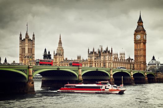 London, the UK. Big Ben, the Palace of Westminster and the River Thames. Red buses, red boat, the icons of England in vintage, retro style