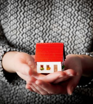 Woman holding a small new house in her hands. Real estate, mortgage, housing concepts etc.