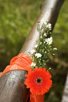 Decorative flowers tied to wooden guard rail at wedding