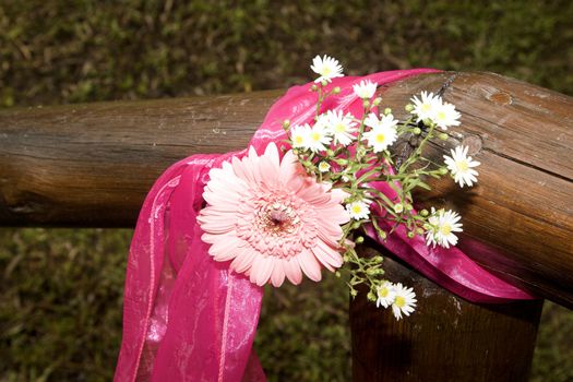 Decorative flowers tied to wooden guard rail at wedding