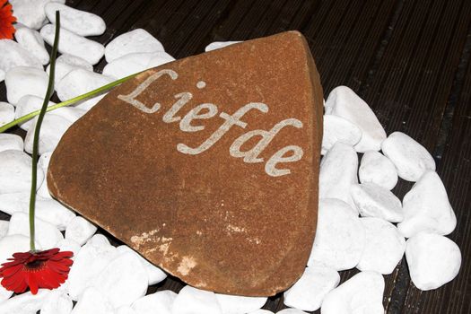 Small sign amongst pebbles with an afrikaans word meaning Love