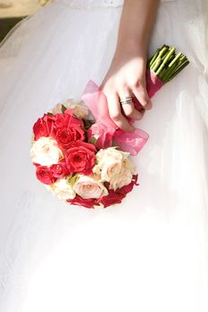 Bride holding a floral bouquet against her dress