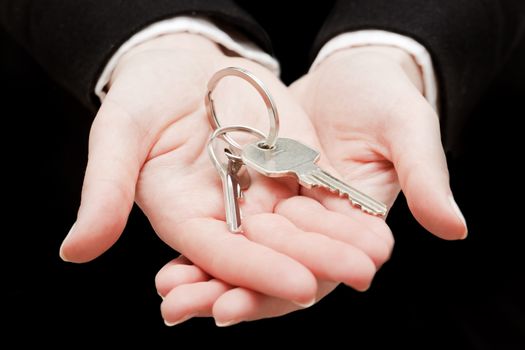 A real estate agent holding keys to a new house in her hands. Real estate industry