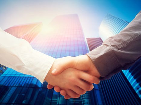 Business handshake on modern skyscrapers background. Deal, success, contract, cooperation concepts 