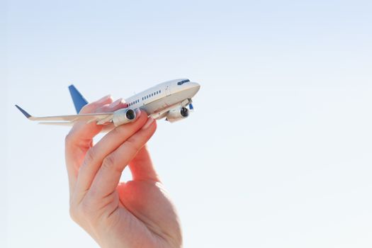 Airplane model in hand on sunny sky. Concepts of travel, transportation, transport, dreaming about holidays