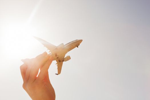 Airplane model in hand on sunny sky. Concepts of travel, transportation, transport, dreaming about holidays