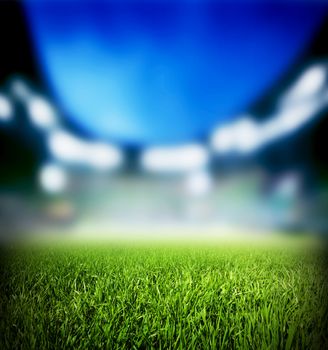 Football, soccer match. Grass close up. Night event lights on the stadium.