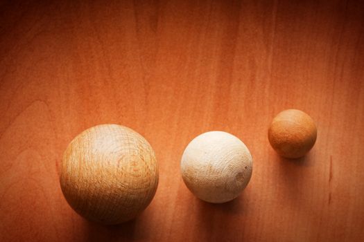 Three wooden balls on a wooden board. Conceptual