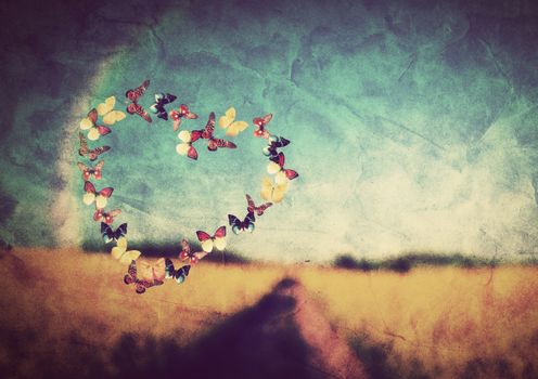 Heart shape made of colorful butterflies on vintage field background. Love, hope concept.