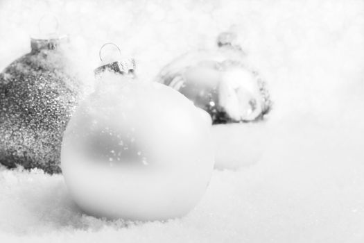 Christmas white glass balls on snow, winter background, frost, glittering lights.