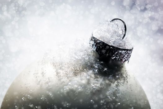 Christmas glass ball on snow, winter background, frost, glittering lights.