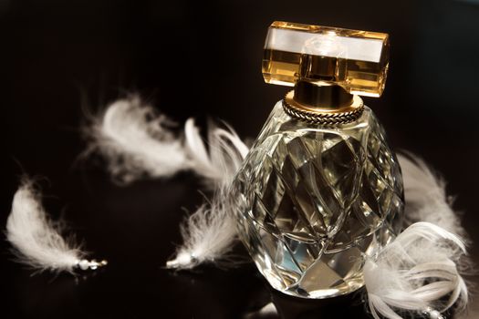 Glass perfume bottle amongst white beaded feathers