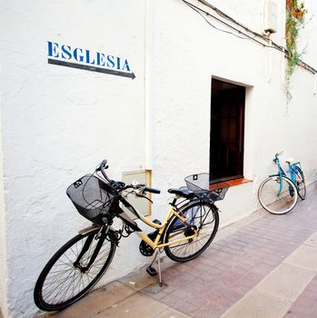 two bicycles at a white wall with arrows and labeled in Catalan "church"