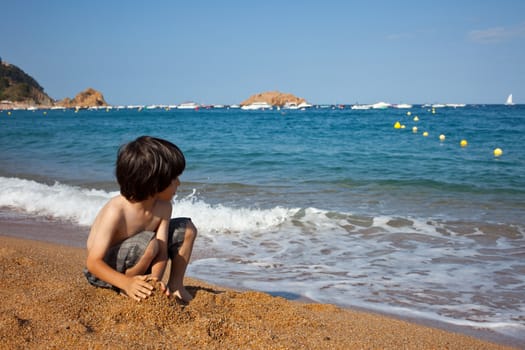 child builds a sand castle on the shore of  sea