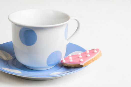 Pink polkadot, heart-shaped cookie on a blue cup