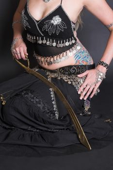 Belly Dancer in black costume balancing a tribal sword