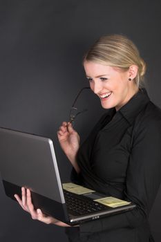 Composed Businesswoman holding a laptop against a black background