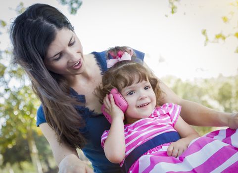 Mixed Race Mother and Cute Baby Daughter Playing with Cell Phone in Park.