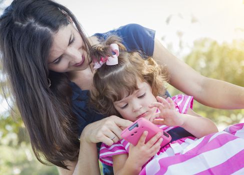 Mixed Race Mother and Cute Baby Daughter Playing with Cell Phone in Park.