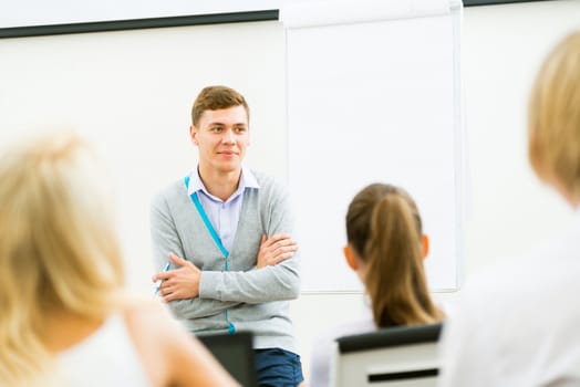 young teacher man talking with students in the classroom