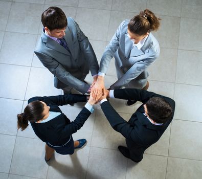 team of four businessmen with folded hands, a symbol of teamwork