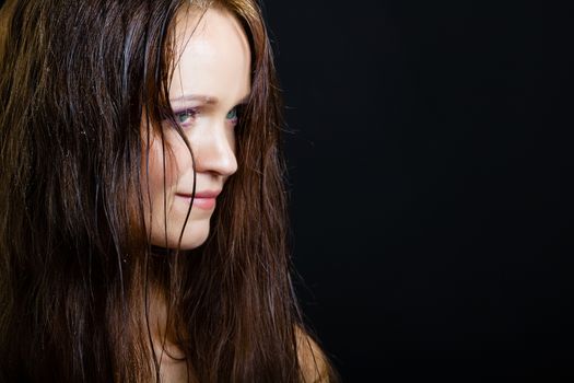 portrait of a young girl with long wet hair on a black background