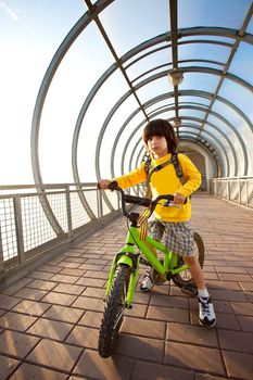 boy in yellow shirt on a bicycle in the covered bridge