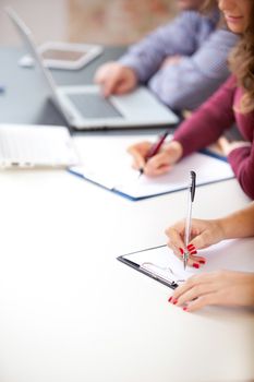 female student hands with a  pen writing on a white notebook