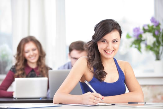 smiling young girl with pen at classroom